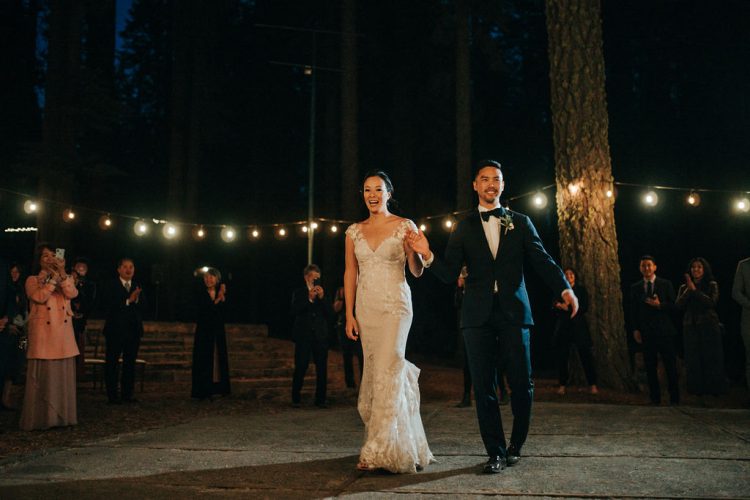 Bride and groom entering the reception under string lights.