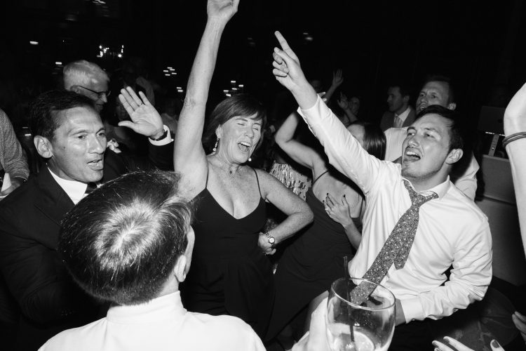 Guests cheering and dancing on the reception dance floor.