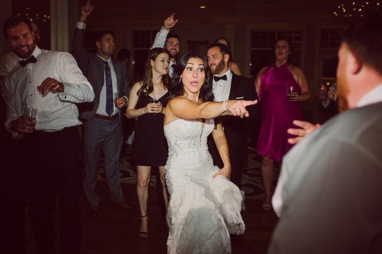 Bride pointing and dancing with guests on the dance floor.