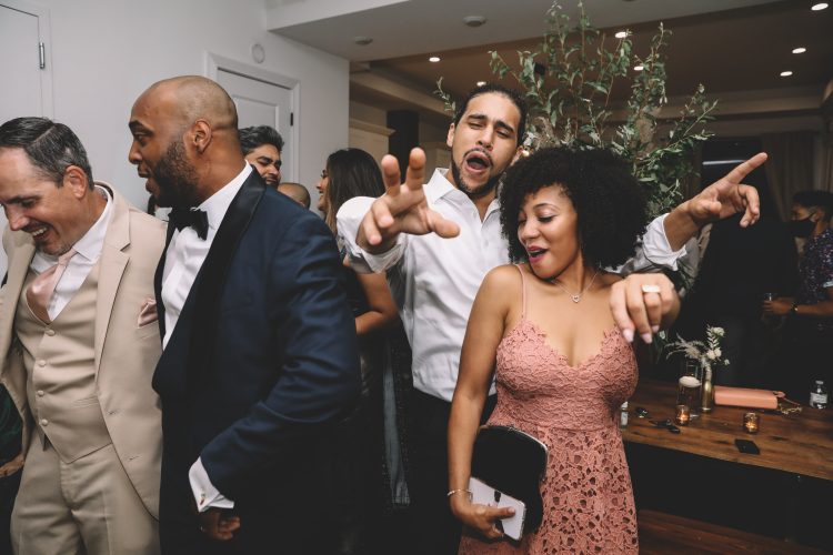 Guests dancing and pointing on the reception dance floor.