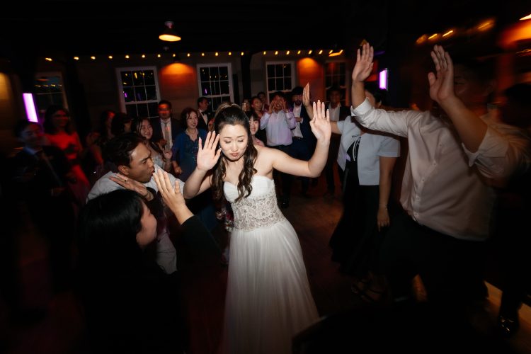 Bride dancing in the center of a lively wedding dance floor.