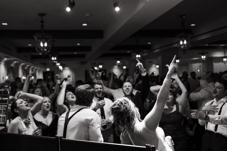 Crowd of guests singing and celebrating on the dance floor.