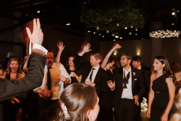 Guests dancing and raising their hands on the dance floor.