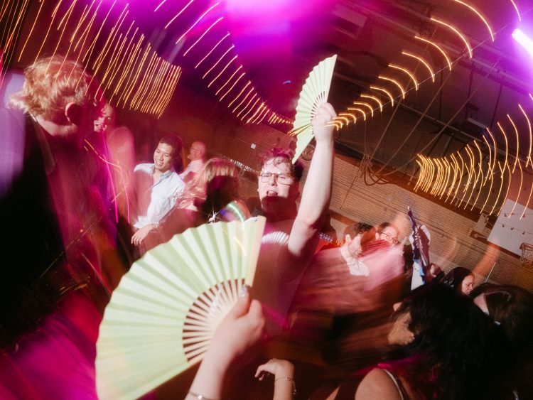 Guest dancing with fans under colorful party lights.