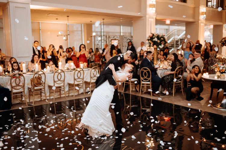 Bride and groom kissing on the dance floor with guests watching.