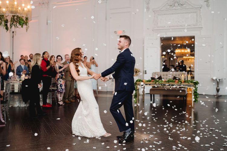 Bride and groom dancing while confetti falls.