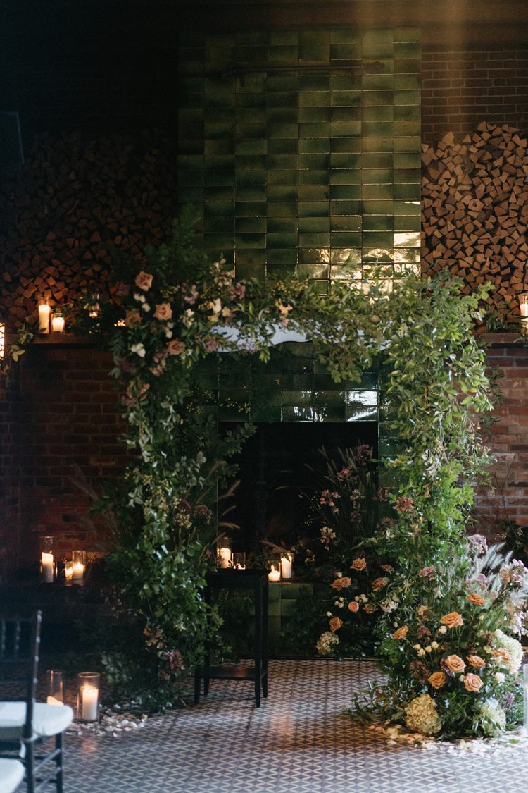 Floral wedding ceremony setup in front of a fireplace at The Bowery Hotel.