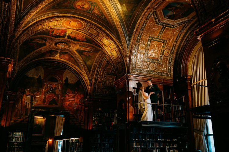 Bride and groom standing together in an ornate library hall at The University Club.