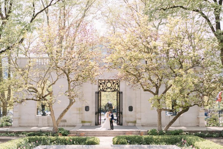 Bride and Groom walking hand in hand in front of a white building at Water Works