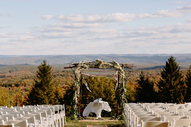 Outdoor wedding ceremony setup with rustic chuppah overlooking mountain landscape at Cedar Lake Estate