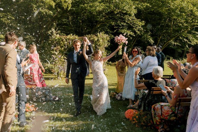 Bride and groom walking down aisle as guests toss confetti after outdoor ceremony at Beaverkill Valley Inn