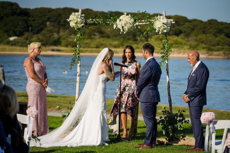 Outdoor waterfront wedding ceremony with floral arch and vows at Gurney’s Montauk Resort Wedding