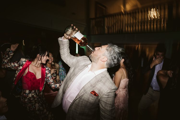 Guest drinking from bottle while dancing at wedding reception