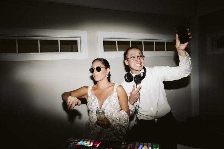 Bride posing with DJ while he takes a selfie at reception