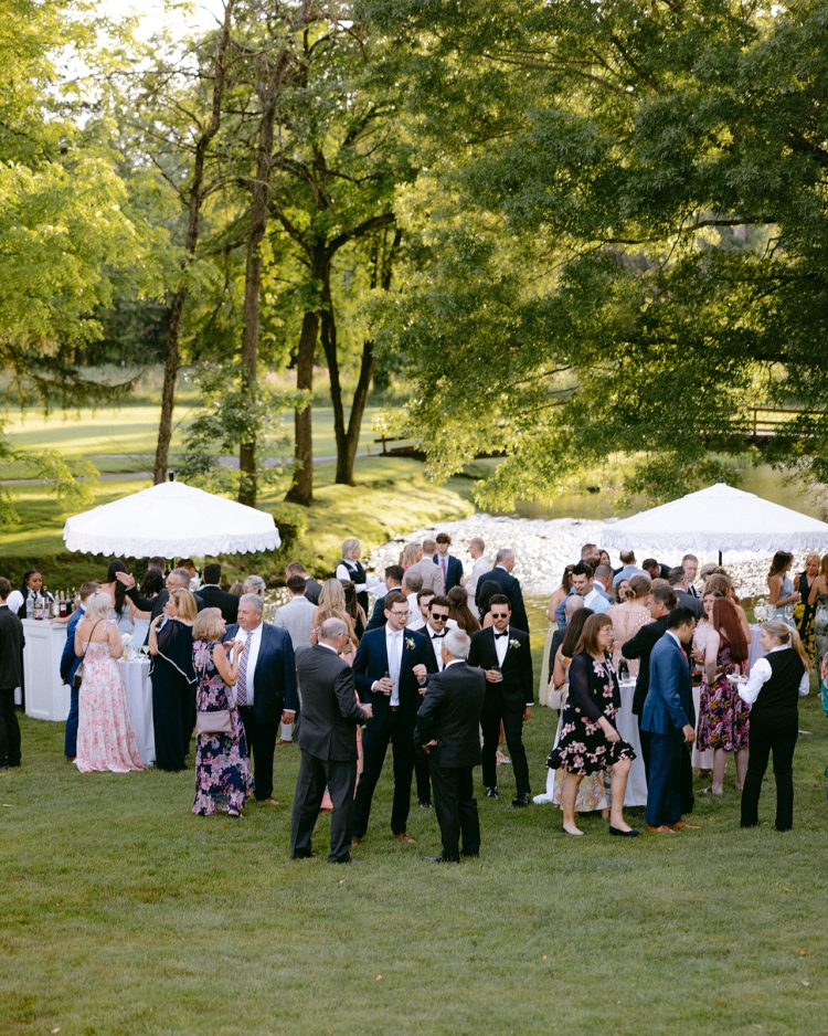 Relaxed outdoor wedding cocktail hour with guests mingling.