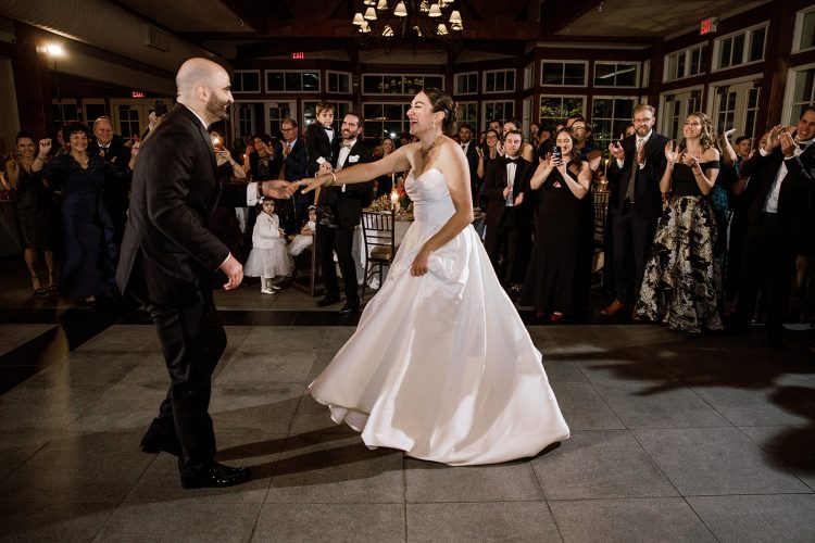 Lively wedding dance with the couple spinning as guests cheer them on.