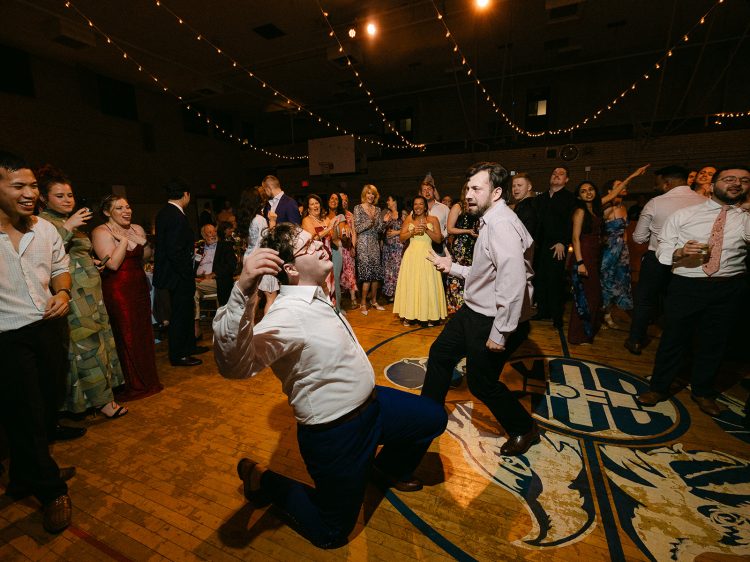 Wild wedding dance floor moment with guests hyping up the action.