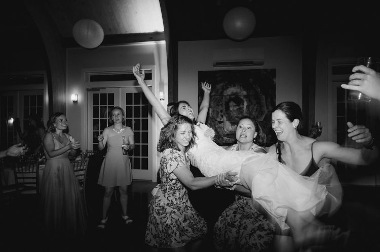 Black and white wedding dance floor with bride lifted by friends.