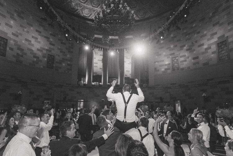 Groom lifted above crowd during lively reception celebration.
