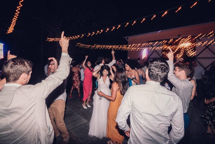 Guests dancing energetically at an outdoor nighttime reception.