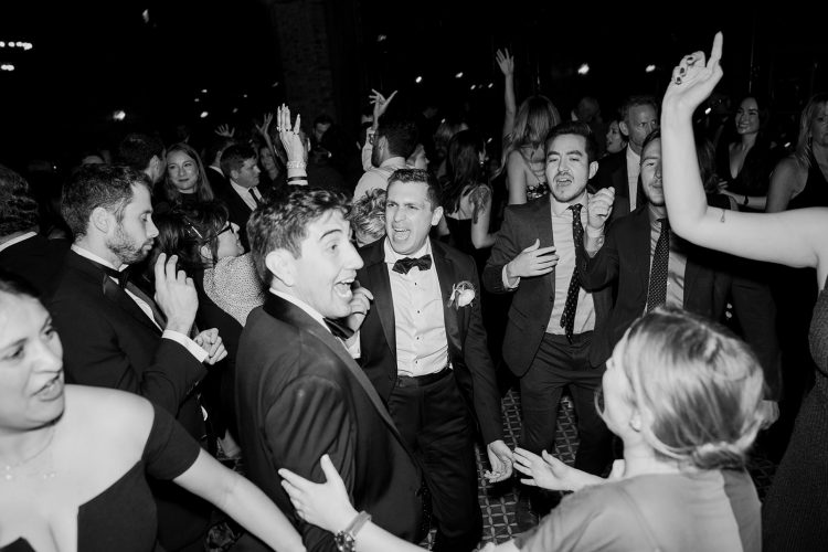 Guests dancing and singing along on a packed dance floor.