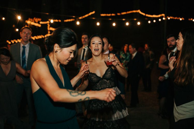 Guests dancing and enjoying drinks under string lights.