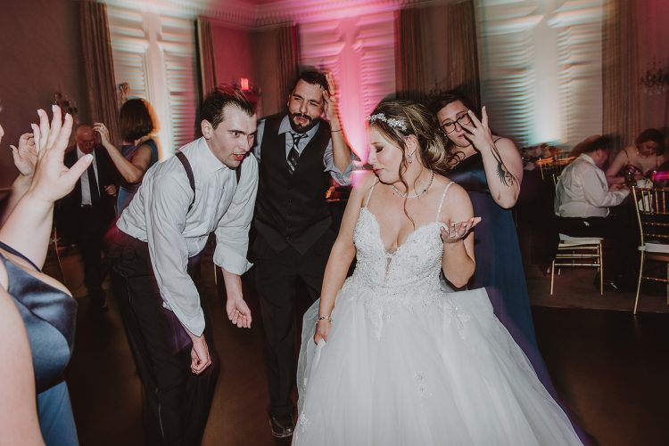 Bride dancing with wedding guests during indoor reception celebration in elegant ballroom setting