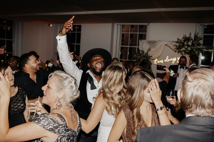 Wedding guests dancing together during lively indoor reception celebration