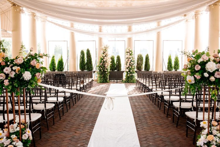 Ceremony aisle setup with floral arrangements in sunlit wedding venue
