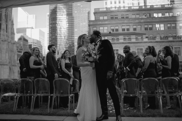Bride and groom sharing first kiss during rooftop wedding ceremony