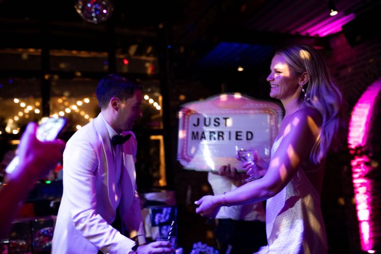 Bride and groom dancing beside a “Just Married” sign at wedding reception