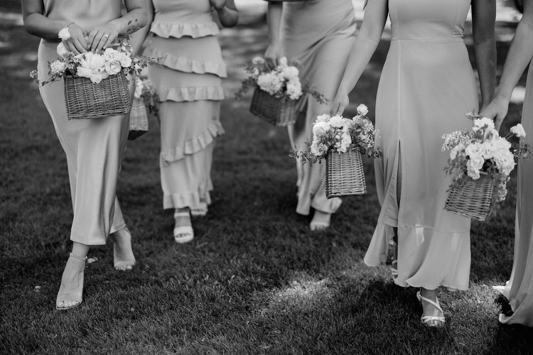 Bridesmaids carrying floral baskets during outdoor wedding ceremony