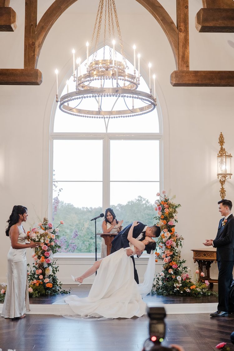 Bride and groom sharing a celebratory kiss during their indoor wedding ceremony