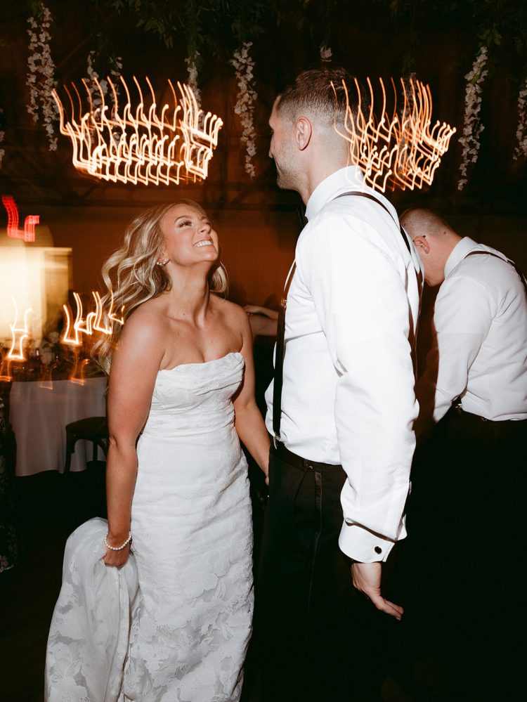 Bride and groom dancing together during their wedding reception with warm motion-blurred lights
