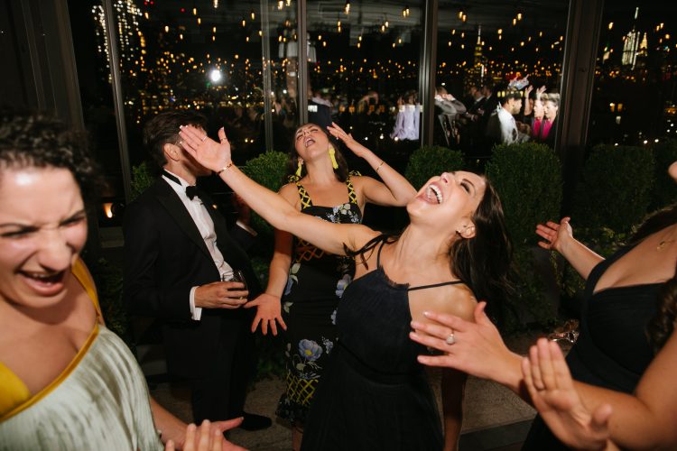 Wedding guests singing and dancing together during reception celebration.