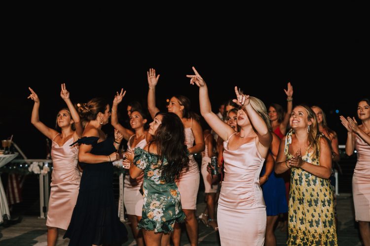 Wedding guests dancing with raised hands during outdoor reception celebration.