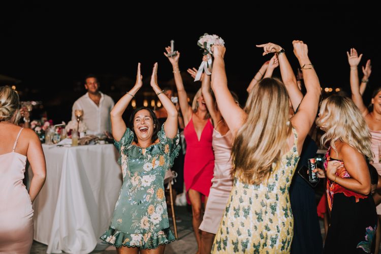 Wedding guests dancing with raised hands during outdoor reception dance floor moment.