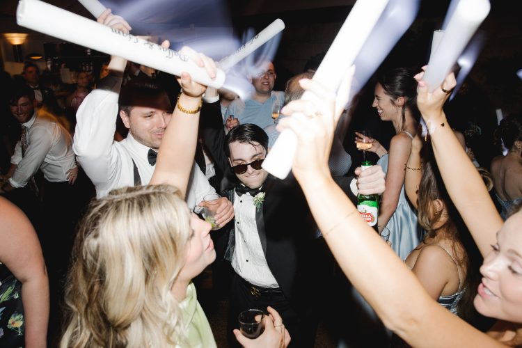 Wedding guests celebrating with foam light sticks during lively reception