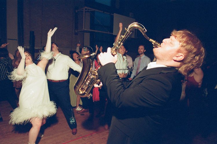 Saxophonist performing on wedding dance floor as guests celebrate